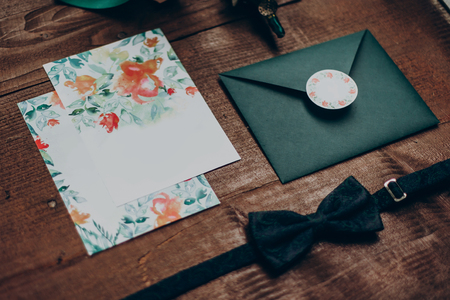 stylish wedding invitation with modern flowers and floral ornaments and bow tie on wooden background top view. rustic wedding morning preparation. space for textの写真素材