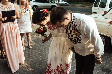 stylish bride and happy groom near car on the background of restaurant getting blessingsの写真素材