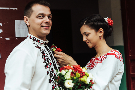 gorgeous brunette bride putting on boutonniere on the groomの写真素材