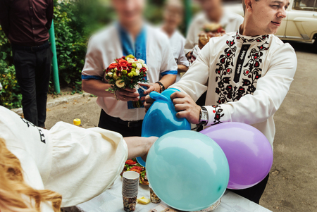 stylish groom having fun with pricking colorful balloons, wedding ceremonyの写真素材