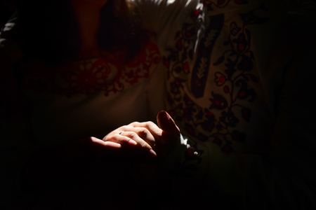 beautiful brunette bride and stylish groom hands with wedding ring in embroidery costumes in the sunlightの写真素材