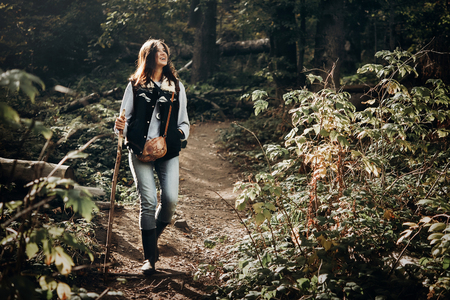 happy hipster traveling and smiling, walking in woods in light. wanderlust and travel concept with space for text. stylish woman hiking. atmospheric epic momentの写真素材