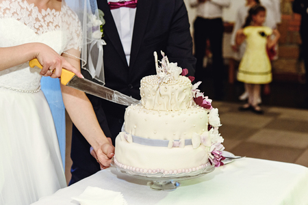 beautiful newlyweds cutting stylish cake with orchids, celebrating weddingの写真素材