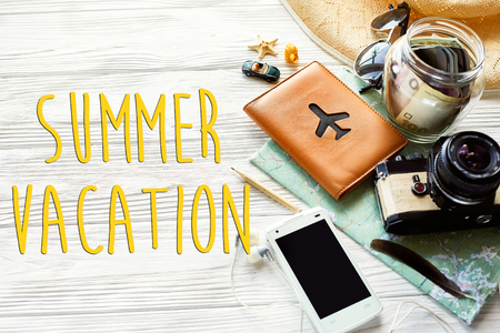 summer vacation text, travel wanderlust concept, space for text. map camera sunglasses passport money phone hat shells car  on white wooden background top view. planning holidayの写真素材