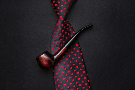 father day concept flat lay. bow tie and  wooden tobacco pipe on black background with space for...