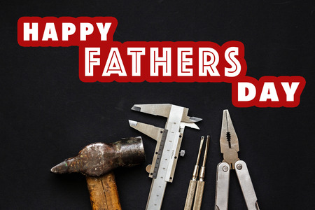 happy father's day text sign on working tools  hammer pliers, screwdriver calipers on black rustic...