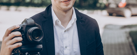 stylish man holding photo camera. professional holding video camera at wedding ceremony,...