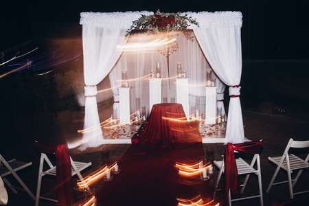 wedding evening decor for ceremony, venue aisle with candles in glass lanterns and arch, stylish wedding decoration for night ceremony in garden, lights. beautiful romantic placeの写真素材