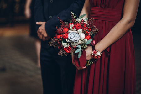 bridesmaid holding rustic bouquet with groomsman,  couple in church during wedding ceremony, religion traditionsの写真素材