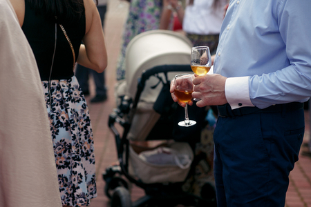 people toasting at wedding ceremony reception. guests holding champagne glasses. open bar in park, family and friends cheering with drinksの写真素材