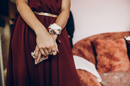 stylish bridesmaids with red and white flowers on boutonniere on hand and in red dress. beautiful woman helping bride in the morningの写真素材