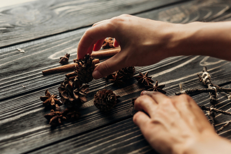 hands holding anise and pine cones on wooden background. stylish rustic winter wallpaper card . space for text. cozy mood autumn. seasonal holidays conceptの写真素材