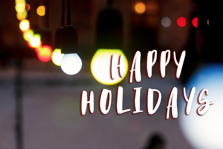 happy holidays text sign on colorful retro garland lights bulbs at street in european city at winter seasonal holidays. decorations outdoors. magic momentsの写真素材