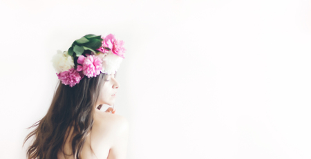 hipster woman with peonies wreath and in white dress posing in morning room. romantic boho bride with peony crown, relaxing moment, space for text. sensual girl portraitの写真素材