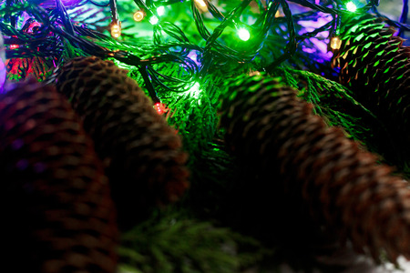 christmas garland lights and pine cones on fir branches. stylish white rustic wooden background....