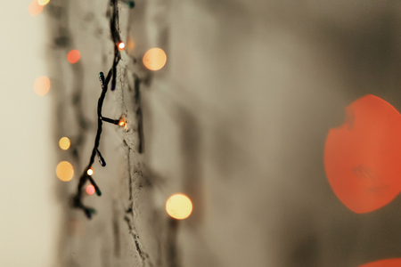 Colorful red and yellow christmas lights hanging on the wall close-up, christmas gift card concept, space for textの写真素材