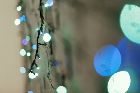 Colorful blue christmas lights hanging on the wall close-up, christmas gift card concept, space for textの写真素材