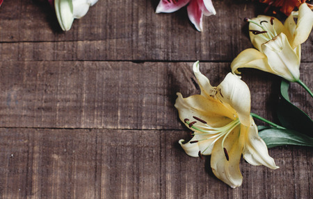 beautiful yellow lily flower on rustic wooden background flat lay. gorgeous bloom minimalistic  on rustic wood backdrop. space for text. greeting card. celebration concept. spring imageの写真素材