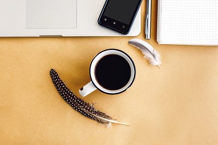 stylish laptop phone and coffee with feathers on craft background,  planning vacation and freelance concept, flat layの写真素材