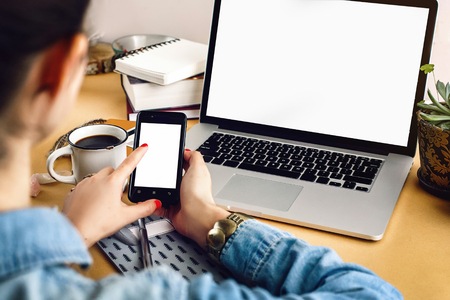 woman holding phone and pointing on empty screen on background of laptop notebook passport  wallet on craft table, top view office homeの写真素材