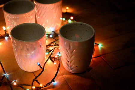 stylish creative ceramics cups and christmas garland lights, holiday celebration conceptの写真素材