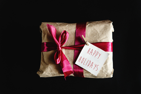 beautiful simple present in craft paper with crimson ribbon and a card, happy holidays textの写真素材