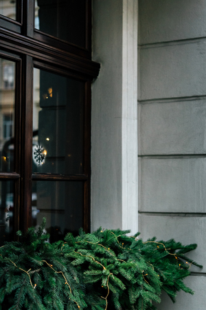 stylish luxury  christmas garland lights on window and green pine, celebration decoration for holidays in the cityの写真素材