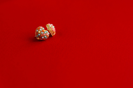 stylish luxury heart earrings with colorful gems on red background, valentine's day conceptの写真素材