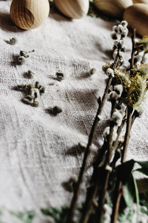 simple wooden easter eggs and willow buds and wax sticks on rustic napkin with embroideryの写真素材
