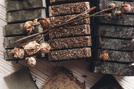 natural soap. handmade herbal soap with wildflowers, healing flowers, mint, dried lavender, top view. eco natural product for skin care. soap on white rustic background with dried herbsの写真素材
