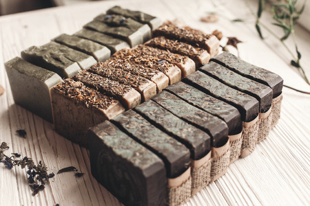 natural soap. handmade herbal soap with wildflowers, healing flowers, mint,  lavender, top view. eco natural product for skin care. soap on white rustic background with dried herbs, space for textの写真素材