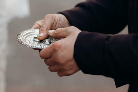 Couple of silver wedding rings on silver plate close-up in church during wedding ceremony, luxury jewelry, two rings in old man's hands, ceremony conceptの写真素材