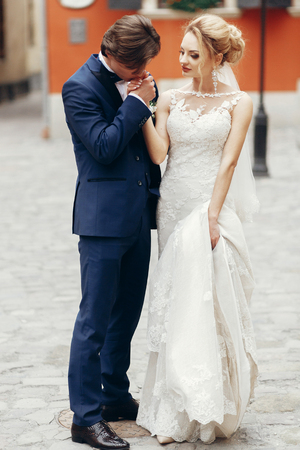 Romantic groom kising hand of beautiful happy bride outdoors, newlywed couple portraitの写真素材