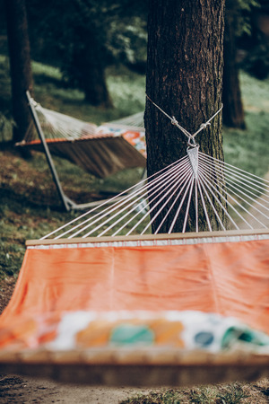 Comfortable orange hammock hanging outdoors in a park, boho hammock tied to trees, camping conceptの写真素材