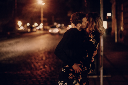 passionate lovers sexually kissing in evening city street at road. stylish gypsy couple in love embracing in night city lights. modern woman and man romantic french atmospheric momentの写真素材