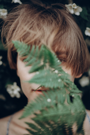 stylish hipster woman with fern leaf embracing. girl portrait with natural herb, windy boho sensual bride. romantic moment. rustic eco wedding concept. beautiful woman posingの写真素材