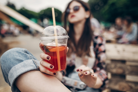 strawberry lemonade in hand. stylish hipster woman in sunglasses with red lips holding lemonade. cool boho girl with cocktail at street food festival. summertime. summer vacation travelの写真素材
