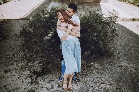 happy stylish couple in love hugging on the beach in summer city. modern woman and man in fashionable white clothes embracing, romantic sensual moment. hipster family on honeymoonの写真素材