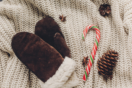 christmas flat lay instagram. gloves candy and anise and cones on cozy sweater on rustic background top view, space for text. xmas seasonal greetings card. winter holidays moodの写真素材