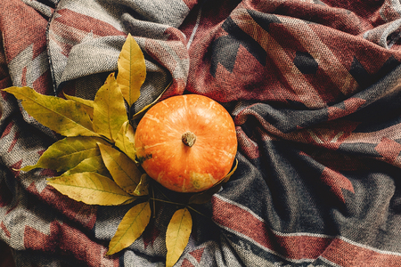 happy halloween or thanksgiving flat lay. autumn pumpkin with colorful leaves on stylish hipster fabric scarf, space for text. seasonal greetings, fall holidays. harvest time. cozy moodの写真素材