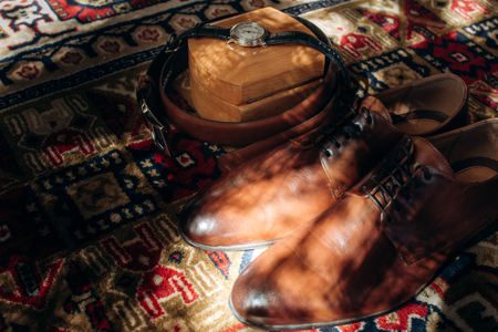Vintage brown leather shoes near elegant black watch and leather top view closeup, groom accessories for wedding ceremony conceptの写真素材