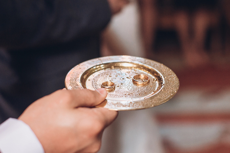 priest golding golden wedding rings on plate in church at wedding matrimony. traditional religious wedding ceremonyの写真素材