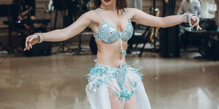 eastern dancing. sexy woman in blue costume performing eastern dance. belly dancer. beautiful woman dancing at wedding reception in restaurantの写真素材