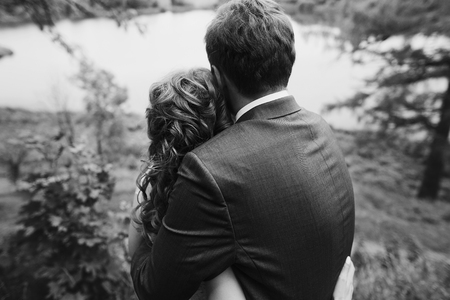 beautiful gorgeous bride and groom walking in sunny park and embracing. happy wedding couple hugging in green garden. happy romantic moments. elopement conceptの写真素材