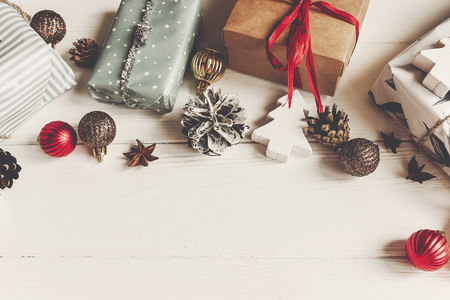 wrapped present boxes with ornaments pine cones anise on white wooden background top view, space for text. christmas flat lay. seasonal greetings card. happy holidays.の写真素材