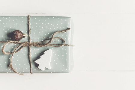 modern christmas wrapped present with ornament and tree on white wooden background top view. merry christmas concept. seasonal greetings card. happy holidays, space textの写真素材