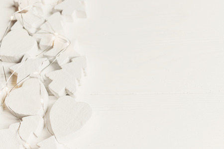 minimalistic scandinavian christmas image. simple wooden white christmas ornaments trees and stars with lights, with space for text. seasonal greetings card. happy holidaysの写真素材