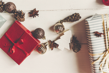 wrapped present boxes with ornaments pine cones anise on white wooden background top view, space for text. christmas flat lay. seasonal greetings card. happy holidays.の写真素材