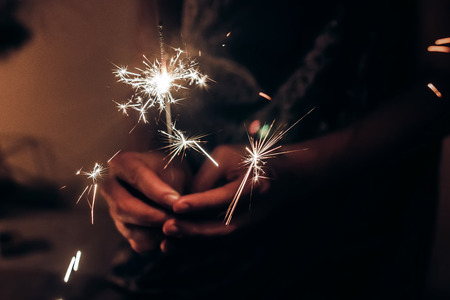 hand holding a burning sparkler bengal light. space for text. burning sparkler closeup in female hand in dark. happy new year and merry christmas concept. happy holidaysの写真素材
