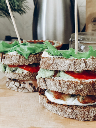 homemade sandwich with prosciutto chicken mozzarella basil tomato salad honey and bread on wooden table. delicious ingredients for italian sandwichの写真素材